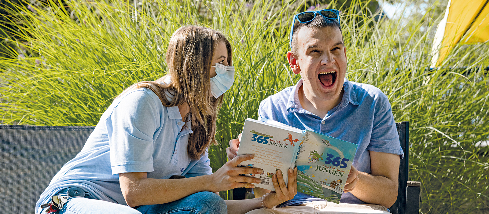 Ein Bewohner und eine Bewohnerin schauen ein Buch an