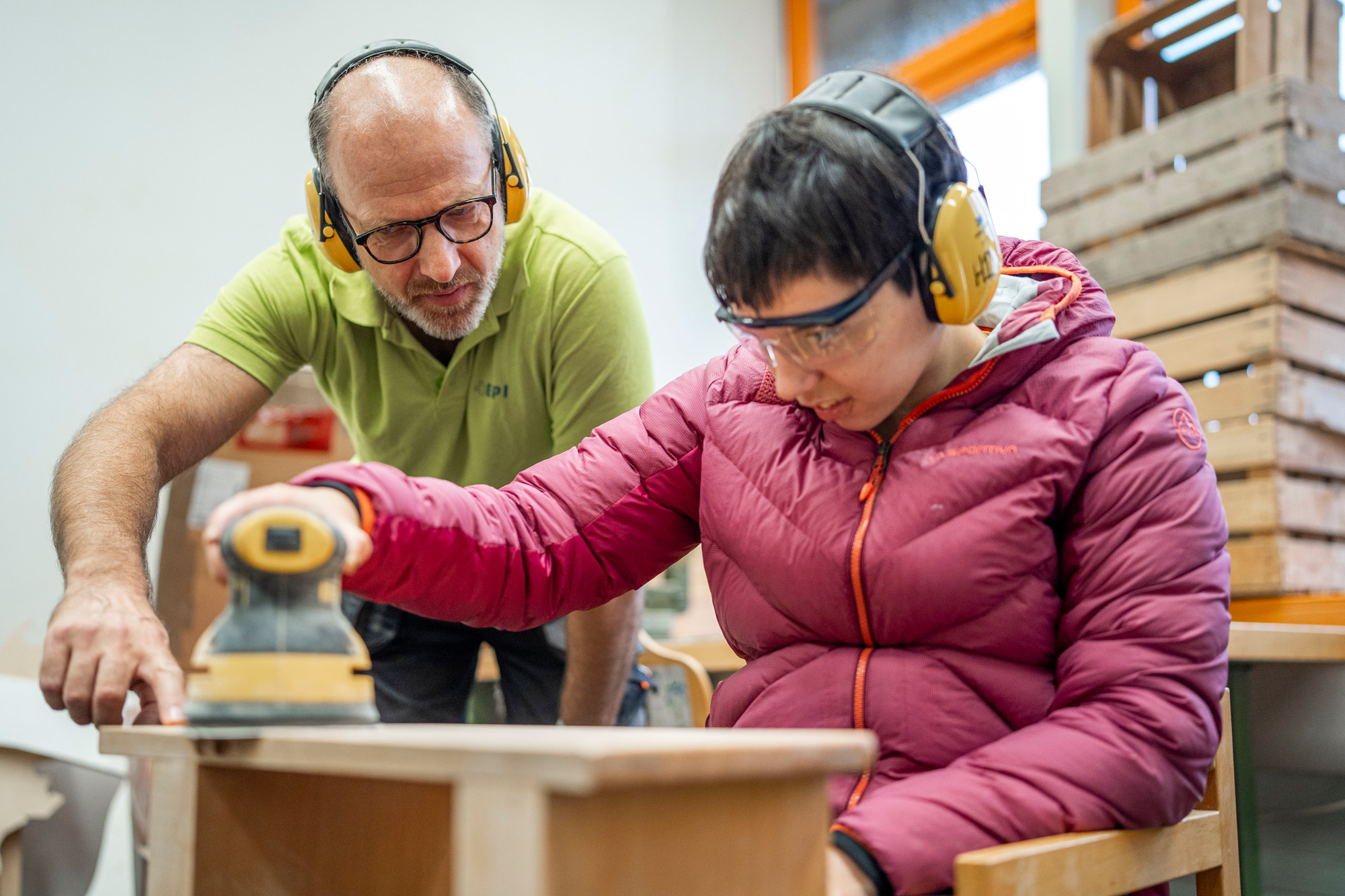 Mitarbeiter begleitet eine Klientin bei der Bearbeitung eines Holzmöbels im EPI MöbelWerk.