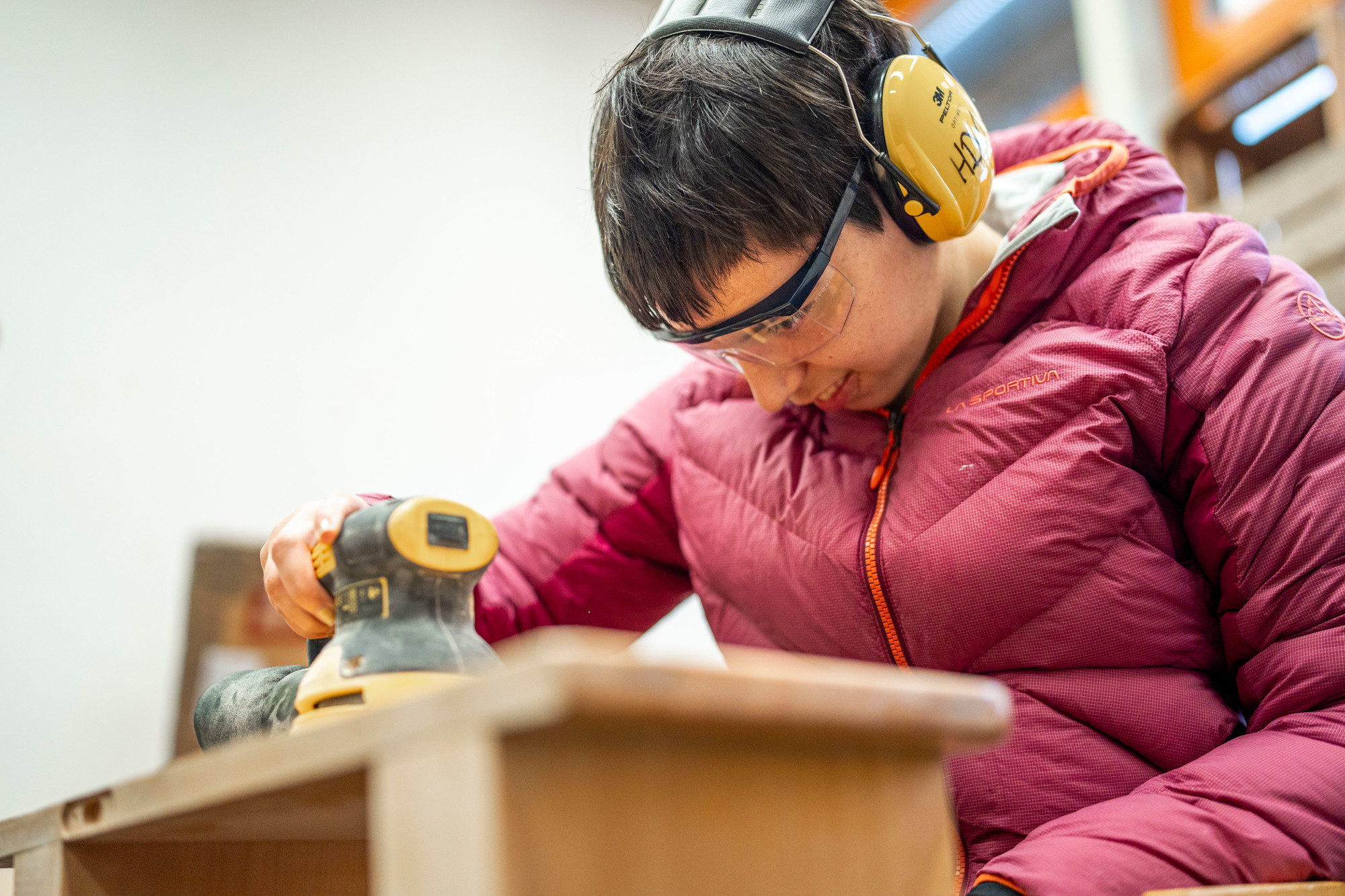 Klientin schleift die Oberfläche eines Holzmöbels im EPI MöbelWerk.